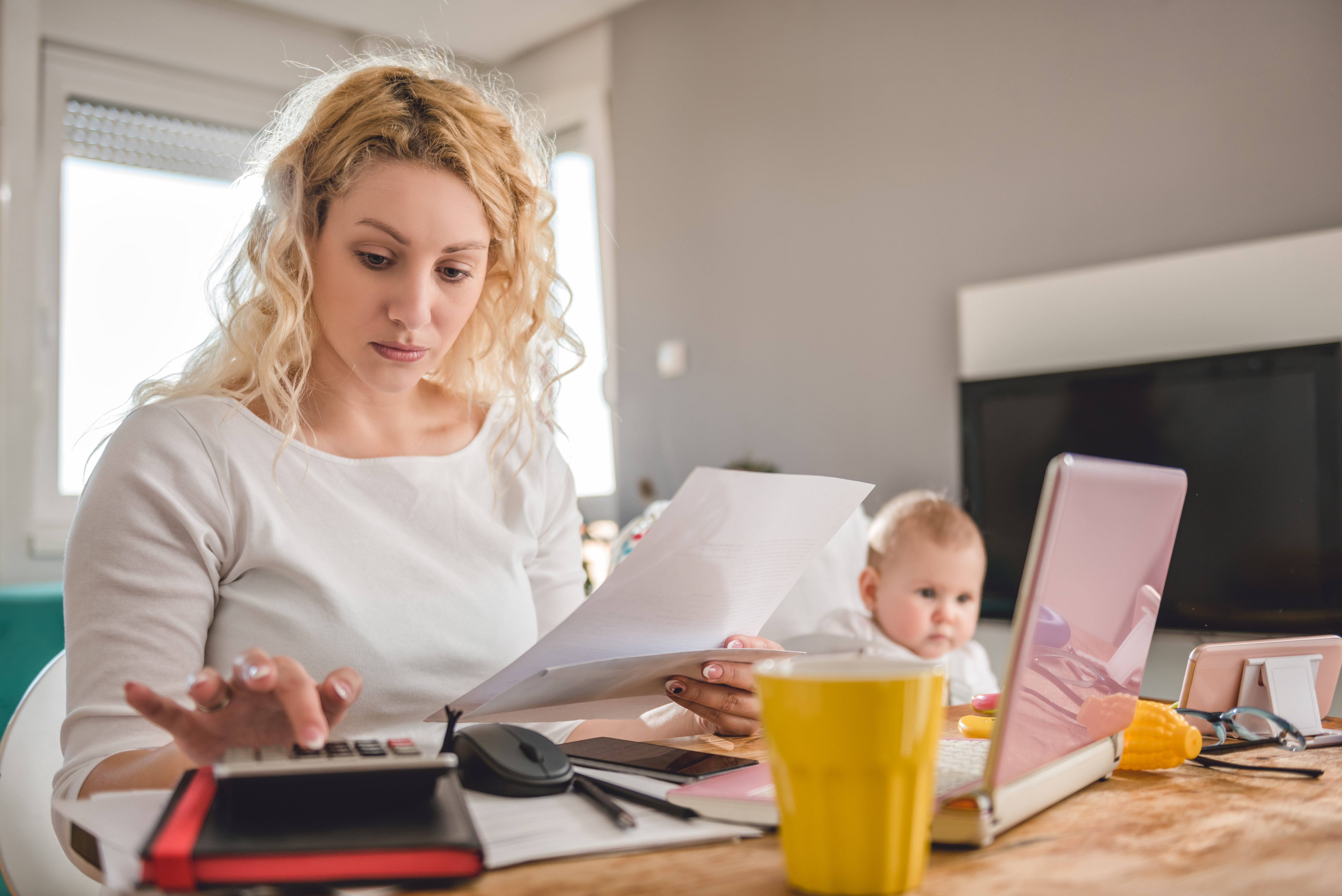 A woman with a child holding a piece of paper while calculating | Source: Shutterstock