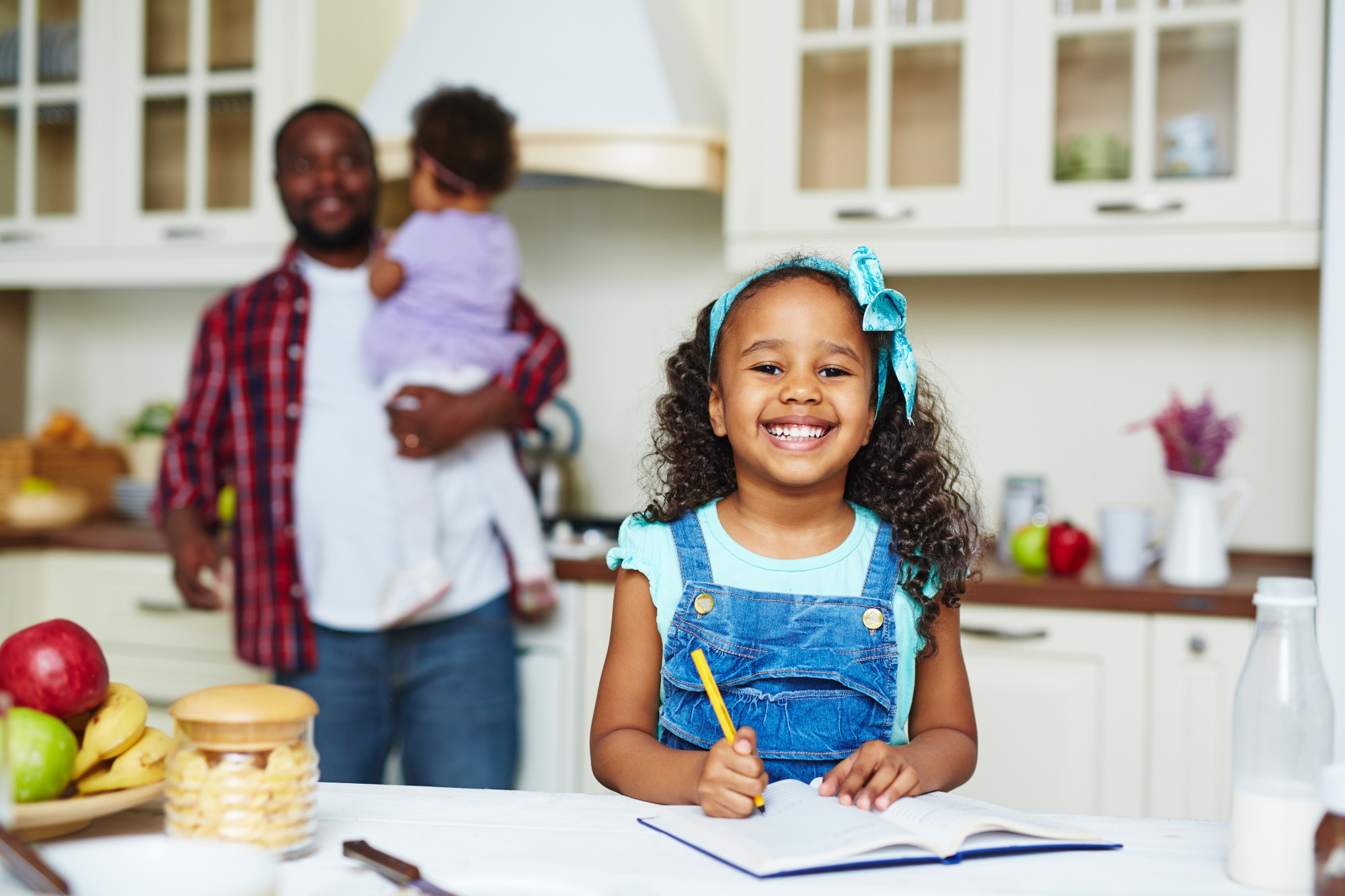 A father carrying his daughter while his other one does homework | Source: Freepik