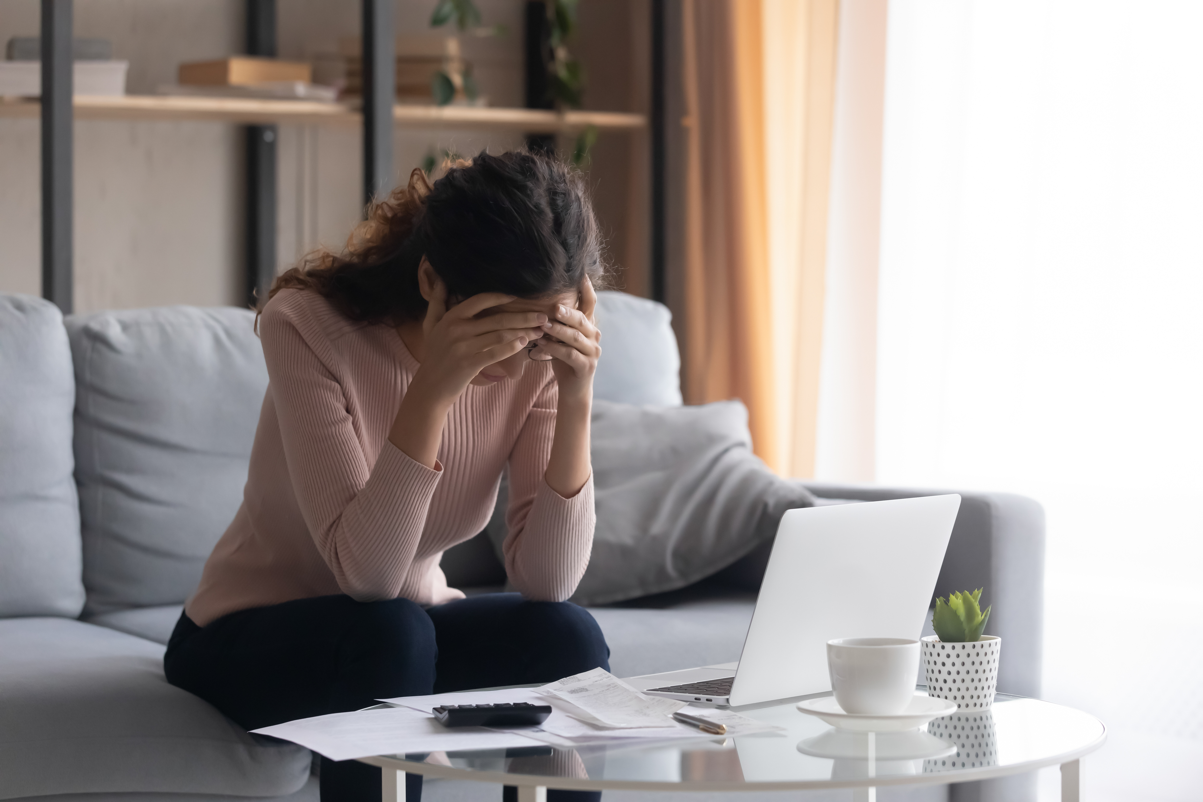 A woman looking stressed with a calculator and laptop in front of her | Source: Shutterstock